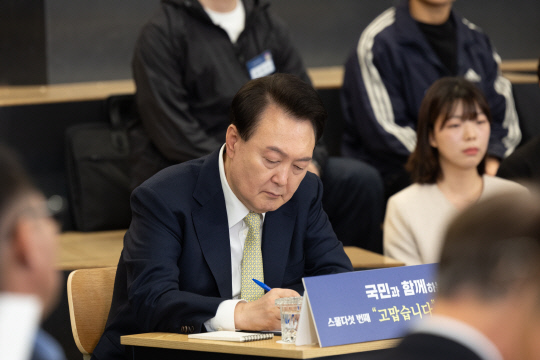 윤석열 대통령이 14일 서울 중구 서울고용복지플러스센터에서 열린 스물다섯번째 '국민과 함께하는 민생토론회'에서 토론자들의 발언을 메모하고 있다.연합뉴스